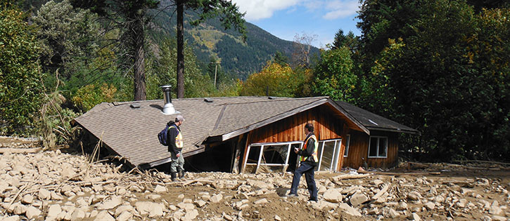 collapsed wood home surrounded by rubble after a disaster